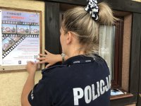 Policjantka zawieszająca plakat z informacją o konkursie
