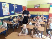 Dzielnicowy Łukasz Woźniak rozdający dzieciom plan lekcji