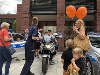 policjantka podaje dziecku dłoń ,dziecko siedzi na motocyklu policyjnym