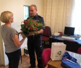 Komendant dziekuje pracownikowi banku wręcza kwiaty i drobny upominek