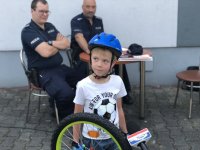 dziecko stoi przy oznakowanym rowerze policjanci w tle