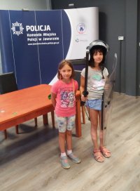 dwie dziewczynki z tarczą i pałką policyjną jedna ma ubrany hełm ochronny