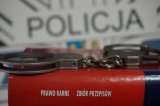 kajdanki metalowe na kodeksie karnym w tle napis policja