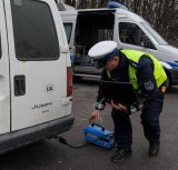policjant podpina do wydechu samochodu analizator spalin