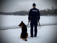 Policjant z psem na tle zamarzniętego zbiornika wodnego