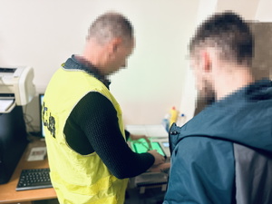 na zdjęciu technik kryminalistyki wykonuje daktyloskopię zatrzymanemu mężczyźnie