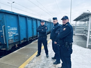 na zdjęciu umundurowany policjant, który stoi z dwoma strażnikami ochrony kolei na peronie