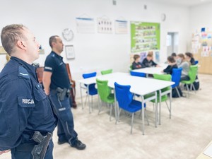 na zdjęciu dwóch umundurowanych policjantów, którzy prowadzą prelekcję dla młodzieży szkolnej w klasie