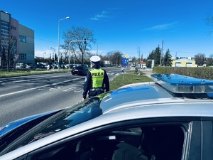 na zdjęciu umundurowany policjant ruchu drogowego obserwuje drogę